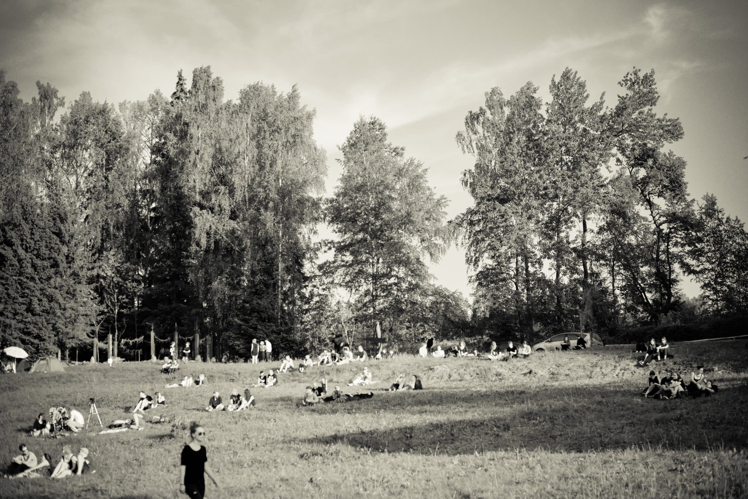 Lankytojai ilsisi pievoje tarp medžių – Postcosmos festivalis, gimęs iš poezijos, muzikos ir pokalbių.