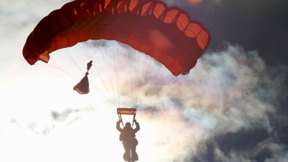 Parašiutininkas ore leidžiasi su raudonu parašiutu – ekstremalios pramogos Lietuvoje: ką veikti adrenalino mėgėjams?