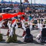 Liaudies šokėjų pasirodymas šalia bolido – įspūdinga Red Bull Showrun akimirka Klaipėdoje su minia žiūrovų.
