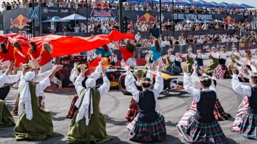 Liaudies šokėjų pasirodymas šalia bolido – įspūdinga Red Bull Showrun akimirka Klaipėdoje su minia žiūrovų.
