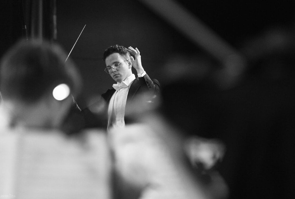 Dirigentas diriguoja orkestrui koncerto metu – Marius Reklaitis įamžintas intensyvios muzikos akimirkos centre.