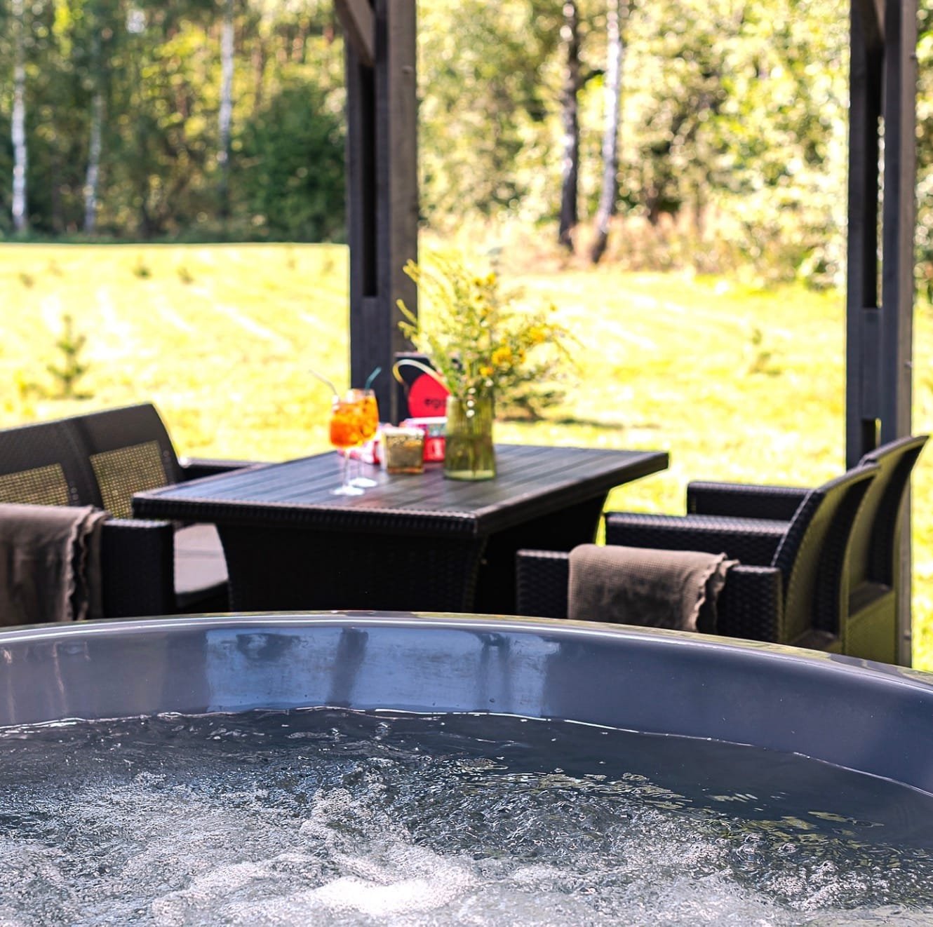 Privatus karštas kubilas dengtoje namelio terasoje su vaizdu į mišką romantiškam vakarui.