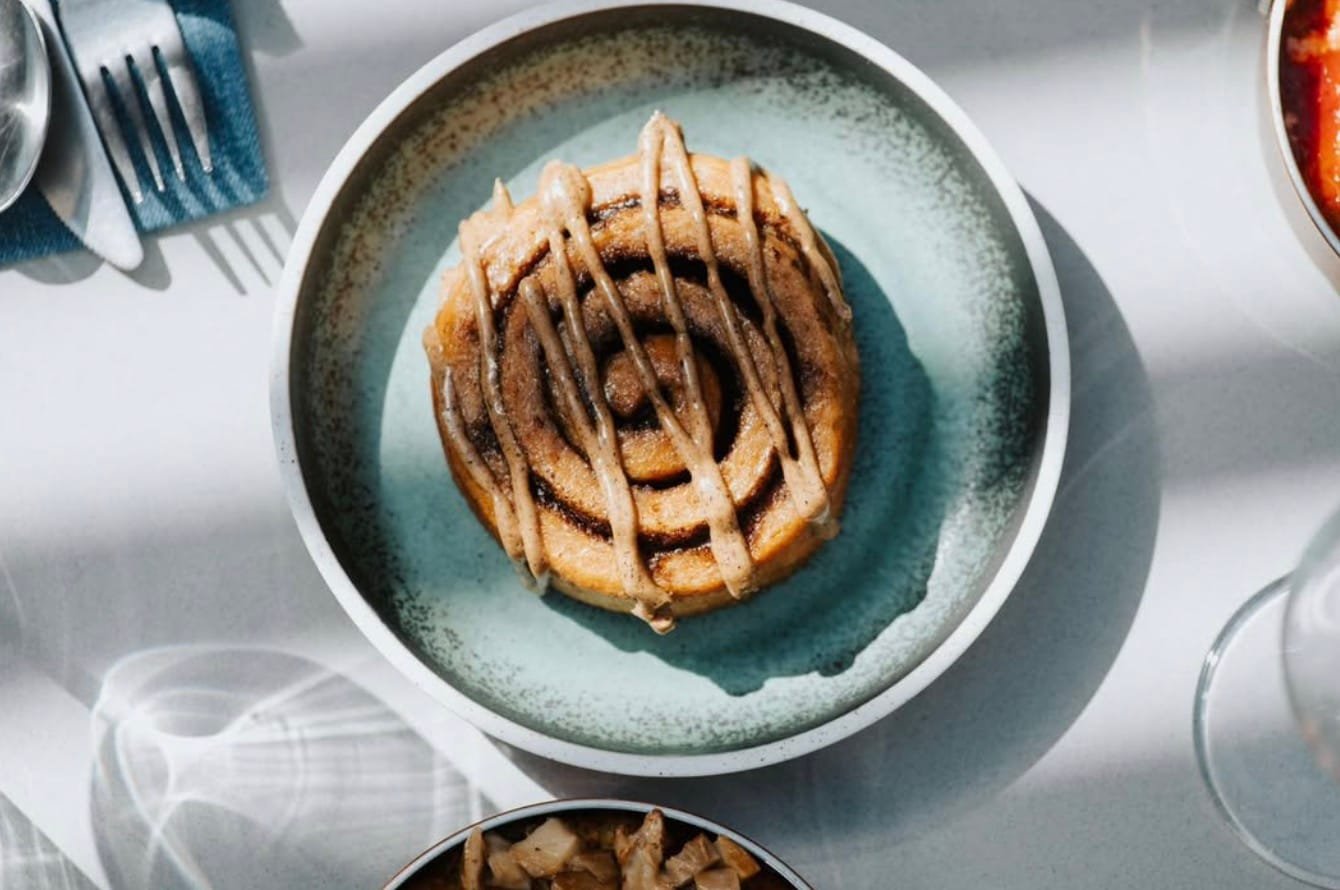 Grūdas kepykla Naujamiestyje, ant stalo padėta traški sluoksniuota cinamoninė bandelė