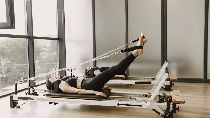 Reformer pilates Vilniuje - įranga studijoje, paruošta treniruotei su spyruoklėmis ir platforma.