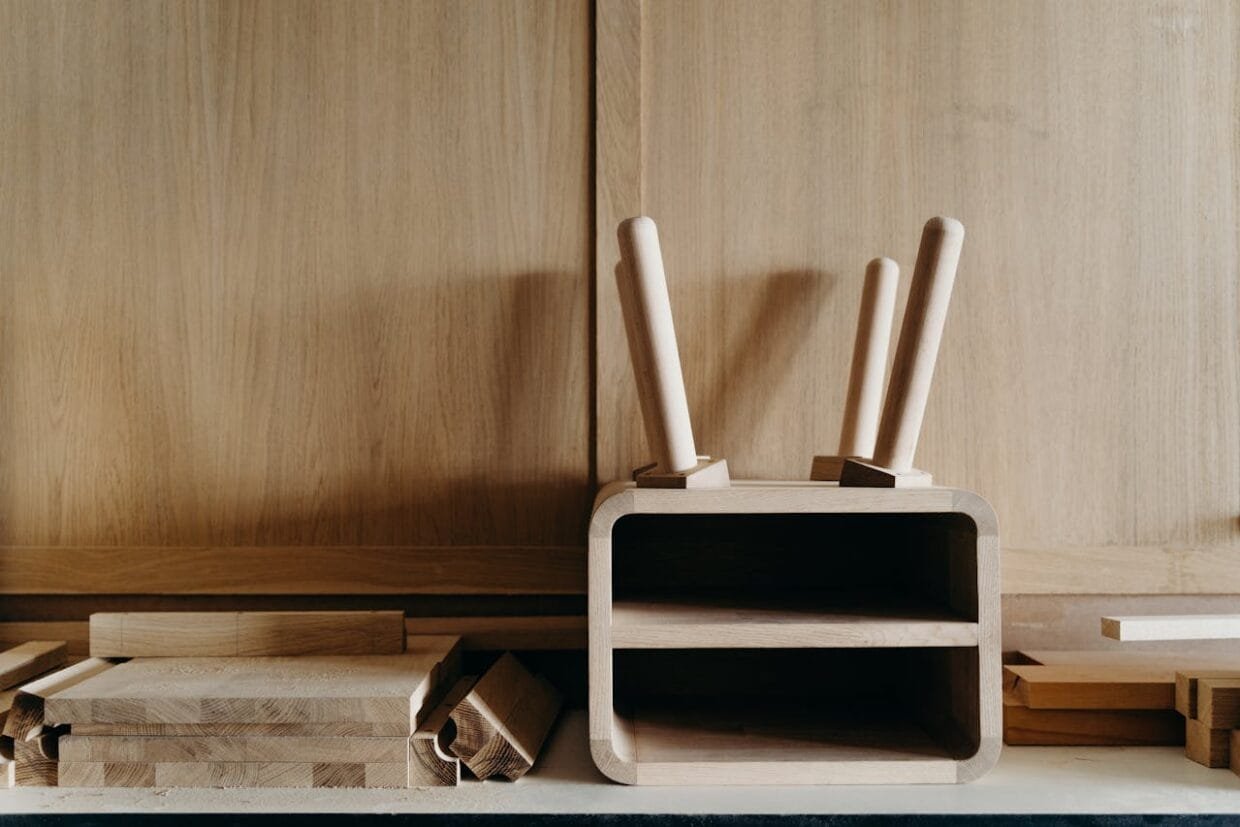 Modernus lietuviškas dizainas namams - natūralaus medžio stalas ir lininės tekstilės detalės šviesiame kambaryje.