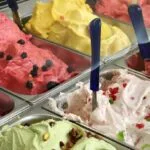 Spalvingos ledainės Vilniuje vitrina su šviežiais itališkais „gelato“ desertais ir besišypsančiais lankytojais.