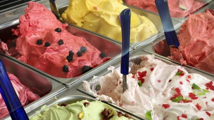 Spalvingos ledainės Vilniuje vitrina su šviežiais itališkais „gelato“ desertais ir besišypsančiais lankytojais.