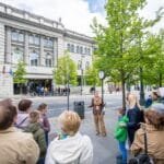 „Open House 2026“ lankytojai ir gidas Vilniuje. Žmonių grupė smalsiai klausosi ekskursijos apie miesto architektūros meną.