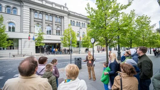 „Open House 2026“ lankytojai ir gidas Vilniuje. Žmonių grupė smalsiai klausosi ekskursijos apie miesto architektūros meną.