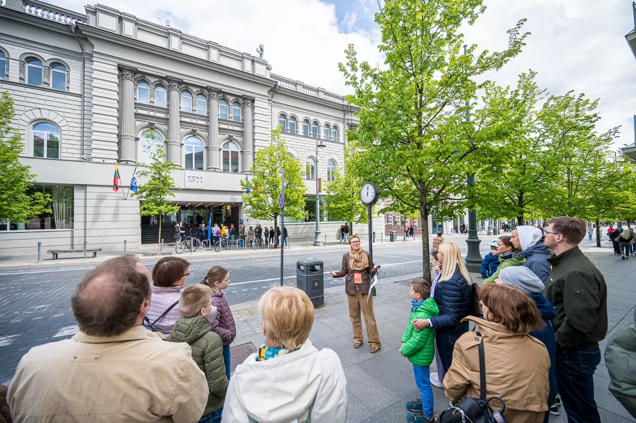 „Open House 2026“ lankytojai ir gidas Vilniuje. Žmonių grupė smalsiai klausosi ekskursijos apie miesto architektūros meną.