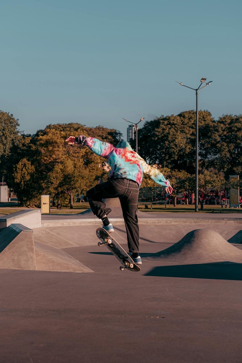 Riedlenčių parkas Vilniuje prie Baltojo tilto su betoninėmis rampomis, kliūtimis ir sportuojančiu jaunimu Upės gatvėje.