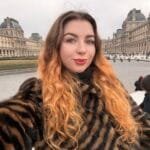 Turinio kūrėja Valerija Kozikaitė šypsosi pozuodama su knyga rankose, spinduliuojanti estetiką ir vidinę ramybę.