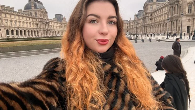 Turinio kūrėja Valerija Kozikaitė šypsosi pozuodama su knyga rankose, spinduliuojanti estetiką ir vidinę ramybę.