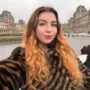 Turinio kūrėja Valerija Kozikaitė šypsosi pozuodama su knyga rankose, spinduliuojanti estetiką ir vidinę ramybę.