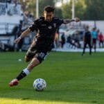 Futbolo sirgaliai su atributika stebi tiesioginę transliaciją po atviru dangumi per FIFA World Cup Vilniuje renginį.