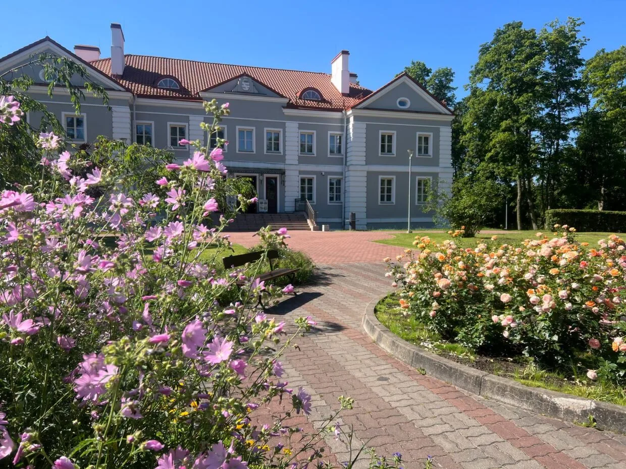 Lietuvos dvarai vasarą: Antazavės dvaro rūmai ir išpuoselėtas angliško stiliaus parkas saulėtą popietę.