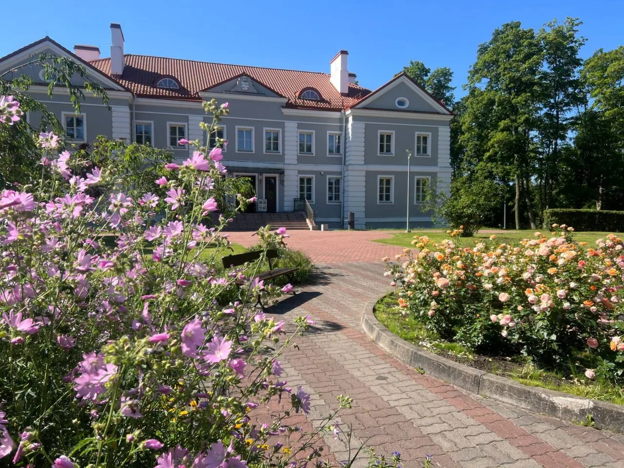 Lietuvos dvarai vasarą: Antazavės dvaro rūmai ir išpuoselėtas angliško stiliaus parkas saulėtą popietę.