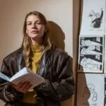 Menininkė Upė Lučiūna laiko knygą.