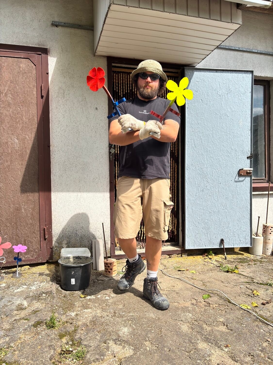 Menininkas Alvydas Marčius lauke laiko spalvotas metalines gėles.