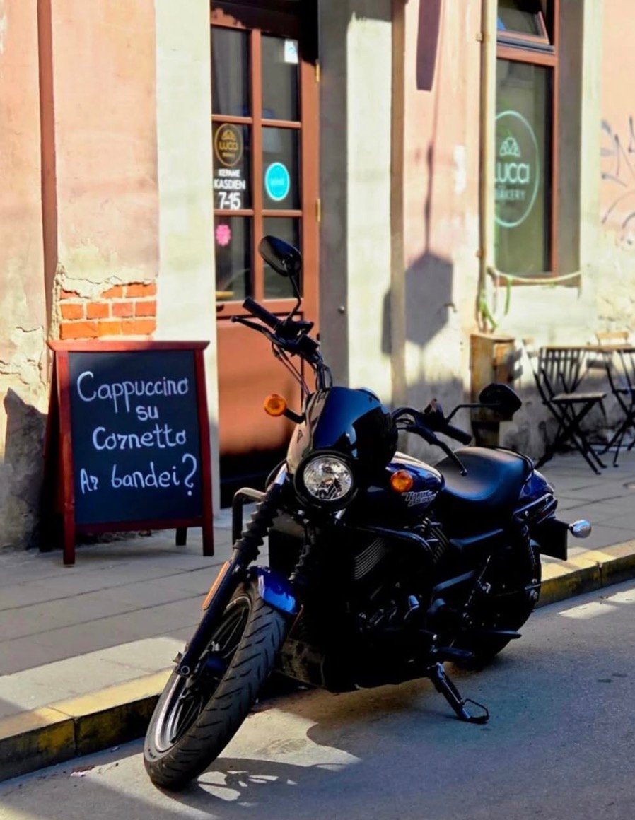Juodas motociklas prie „Lucci Bakery“ eksterjero – stilingos kavinės Kaune vaizdas.
