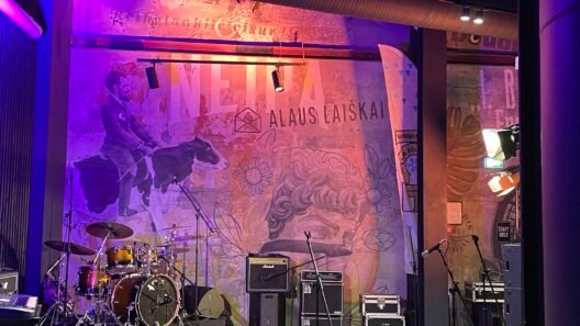 Kultūros erdvės Kaune - muzikos scena su būgnais ir garso įranga baro interjere.