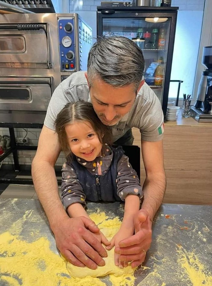 Šefas Fabrizio moko vaiką pašauti picą į krosnį